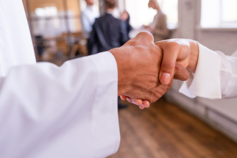 Fotografia della stretta di mano tra un prete e una fedele